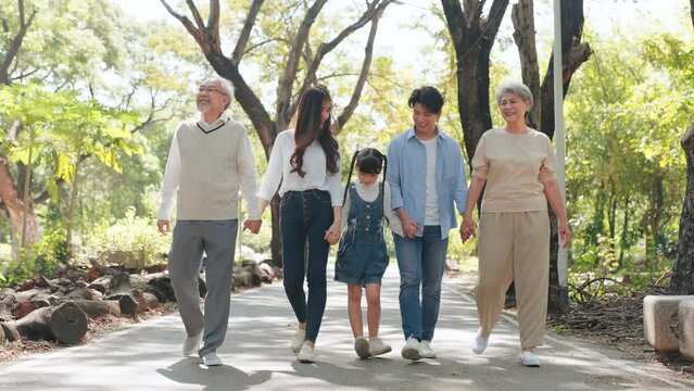 Happy big Asian family on summer walking together in the park, Multi-generation family walking in the outdoor garden