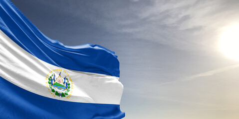 El Salvador national flag cloth fabric waving on beautiful grey sky Background.