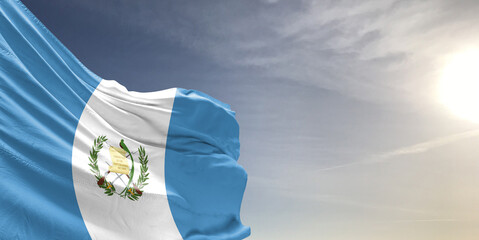 Guatemala national flag cloth fabric waving on beautiful grey sky Background.