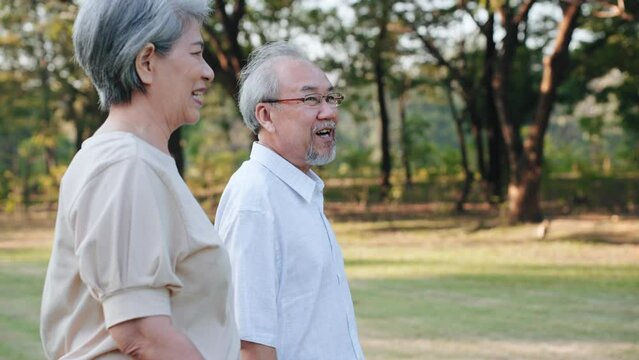 Asian senior couple holding hands walking in garden on weekend, Relax time of retire concept