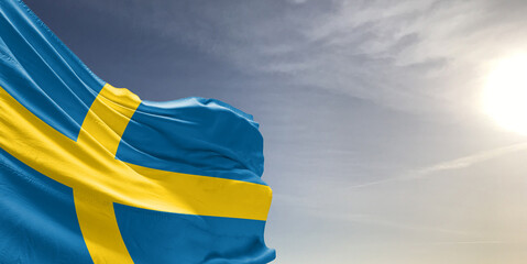 Sweden national flag cloth fabric waving on beautiful grey sky Background.