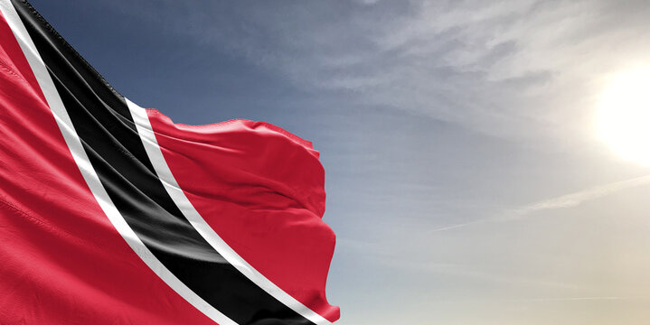 Trinidad and Tobago national flag cloth fabric waving on beautiful grey sky Background.