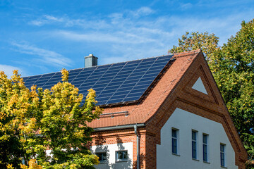 Photovoltaik -Anlage auf einem mit Ziegel eingedecktem Dach vor blauem Himme
