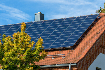 Photovoltaik -Anlage auf einem mit Ziegel eingedecktem Dach vor blauem Himmel
