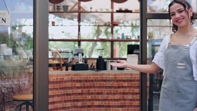 Barista man and woman wearing apron invite guest and welcoming guest at storefront in coffee shop or restaurant.