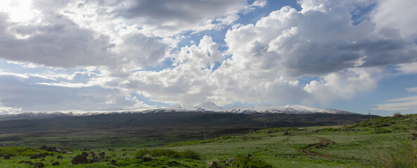 Mount Aragats against a picturesque backdrop of dramatic clouds on a beautiful sunny spring day.