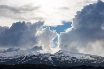 Mountain Aragats partially covered by snow, under dramatic clouds, low angle view