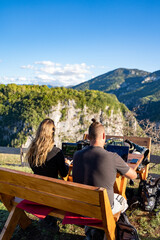 Young couple working location independent as digital nomads in the sunshine on a mountain in...