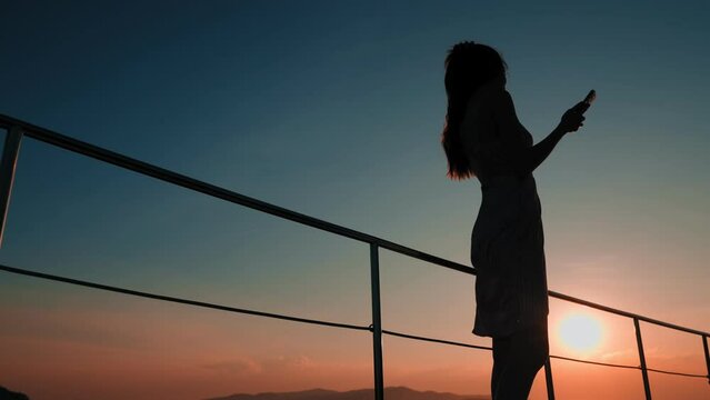 Silhouette of Cheerful asian sexy woman wearing a short chiffon dress dancing at the deck during yachting in twilight time, Summer holiday and long weekend concept. 