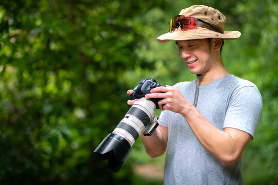 happy asian photographer travel and take photo with digital camera and backpacker trail trekking in nature forest on high mountain, hobby activity in weekend