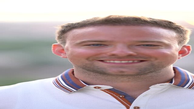 Vertical video of blond man with blue eyes smiling