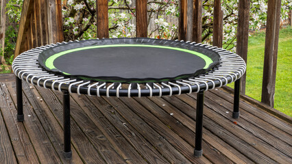 mini trampoline for fitness exercising and rebounding in a backyard patio, springtime scenery