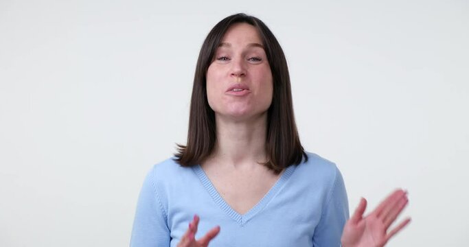 A Caucasian woman standing on a white background, talking and gesturing while expressing her thoughts or ideas. She appears to be a video blogger, engaging her audience with her mood.