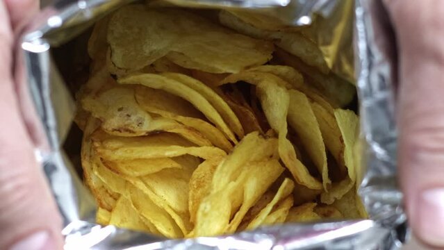 Indulge In The Delightful Unveiling: Watch As Unidentified Hands Gracefully Open A Bag Of Tempting Potato Chips In Mesmerizing Slow Motion