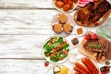 Summer BBQ food side border over a white wood background. Various grilled meats, vegetables and smores. Above view with copy space.