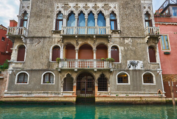 Fototapeta na wymiar Boats covered from rain parked in the water next to the house in canal of Venice. Water transport and transportation theme.