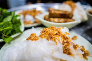 Banh cuon - Vietnamese steamed rice rolls with minced meat inside accompanied by bowl of fish sauce. Detail.