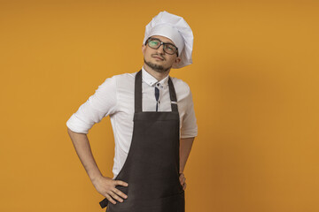 a male cook in glasses, a black apron and a beret put his hands on his hips and looks suspiciously...