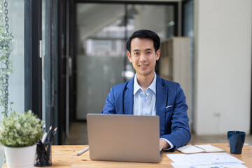 Upset businessman behind laptop computer working inside modern office room.