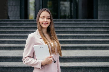 Woman marketer in suit smiling holding a tablet and looking at camera