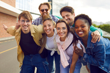 Group happy multiethnic young people man and woman with smile posing during walking around city rejoicing at long-awaited meeting with student friends stand on sidewalk next to road in summer day