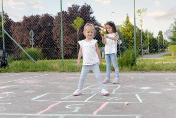 Two little girls playing hopscotch ,We love to play together