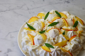 meringue dessert decorated with whipped cream and peach slices