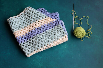 Crocheted top and yarn on a turquoise background with copy space. Crochet fashion concept. Hand...