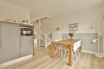 a kitchen and dining area in a house with white walls, hardwood flooring and light grey painted wallpaper