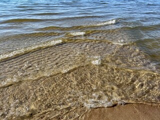 Transparent sea water and sandy bottom, ripples on the sea water, natural sea water background