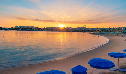 View of the seashore and a sandy beach of Malta illuminated during the golden hour at sunrise