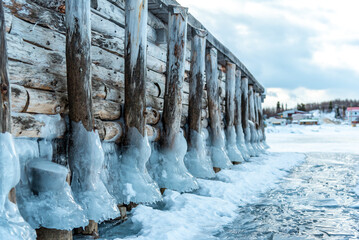 Beautiful frozen boat dock in winter time season with ice covering the wooden, old posts of the...