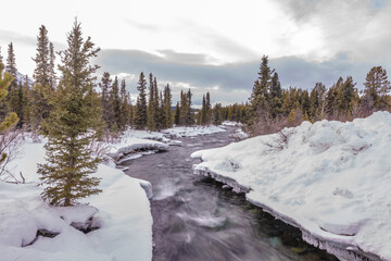 A winter wonderland seen in northern Canada, Yukon Territory during freezing cold season with deep snow along a wilderness river, creek.