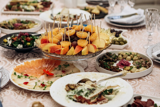 Banquet hall table set for event party wedding. Decorated interior in restaurant with snacks, salads, glasses, alcohol, fruits

