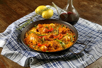 Valencian paella with porrenes of red wine on the wooden table