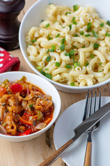 Macaroni and shrimp sauce served in white ceramic bowls on a wooden table ready to eat