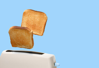 Toasted bread and toaster over light blue background. Space for text