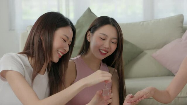 young Asian friends use nail polish to paint each other's nails