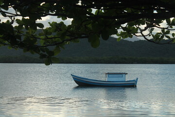 Fototapeta na wymiar A tranquil sunset over calm waters with a boat near Ilha do Cardoso in Cananéia