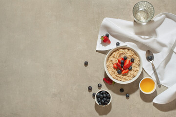 Oatmeal with berries and honey on a gray table