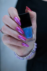 Woman hand with long nails manicure and light pink and blue nail polish