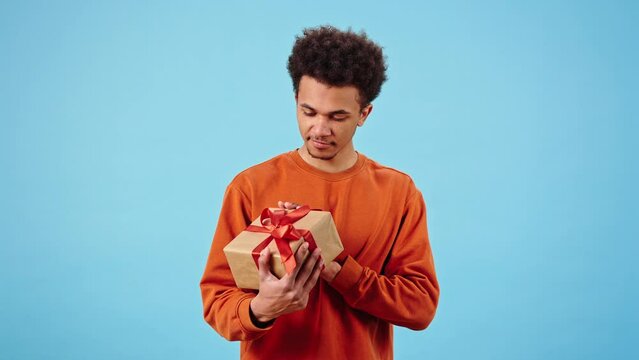 Happy African American man examines gift box with red bow