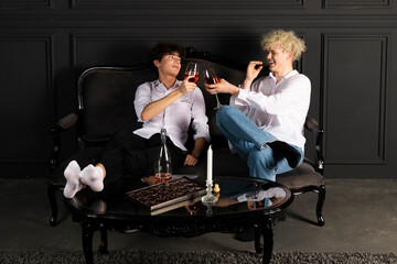 Two young guys celebrating with a bottle of champagne. Romantic evening of the gay couple. blonde and brunette having fun together.