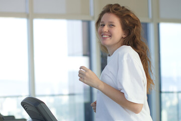 Happy young fit woman training in the gym, running jogging on treadmill, doing cardio exercise and smile. Healthy lifestyle, sport, fitness concept