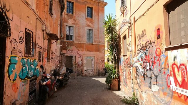 Walking through an alley covered in graffiti in the Trastevere neighborhood of Rome in Italy.