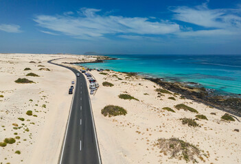 Aerial mid level panoramic view of Moro Beach and the road between the coast and Parque Natural sand dunes heading to Corralejo Fuerteventura Spain