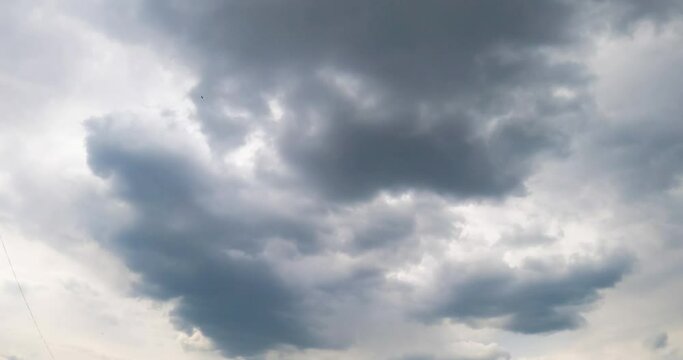 Heavy rain clouds moving by the sky. Grey cloudscape covering the horizon. Timelapse. Low angle view.