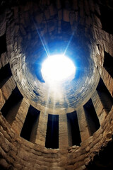 Looking up from inside a well at a small circle of sky, holy light. AI generative