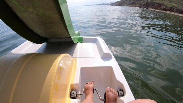 Woman floating on catamaran. Person pedaling with her feet and swimming on catamaran on sea surface with waves on sunny summer day. Active lifestyle recreation leisure sport POV