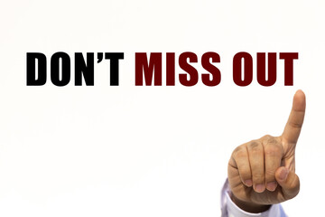 Don't miss out text on white wall background with businessman's finger point at the message with empty space. This message can be used as business concept about don't miss out.